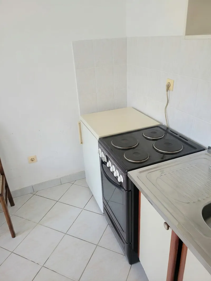 Kitchenette with cooker, stainless steel sink and tiled splashback