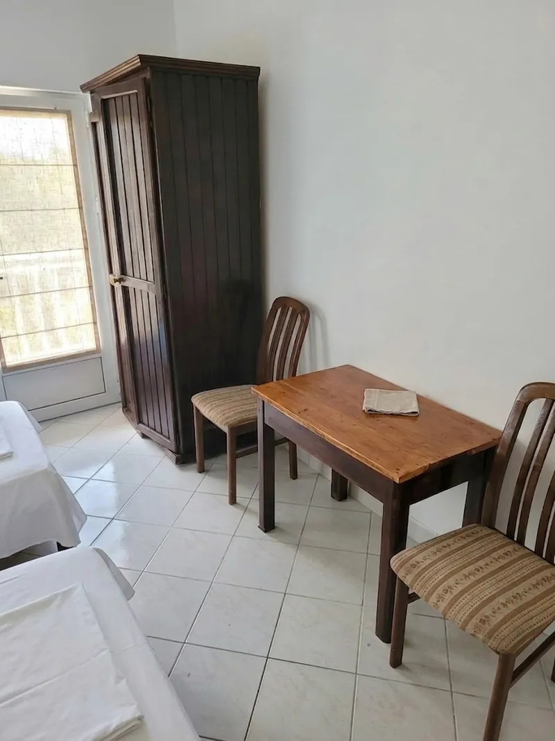 Wardrobe, wooden dining table and two chairs beside the window
